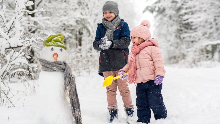 Kids builds a snow man.
